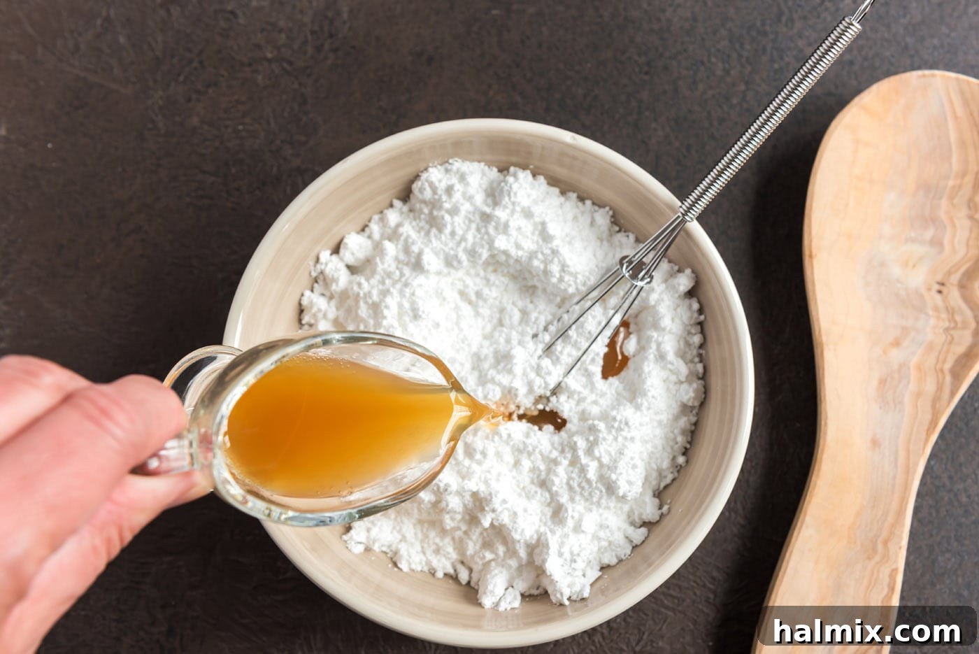 Pouring apple cider into powdered sugar to create a smooth glaze