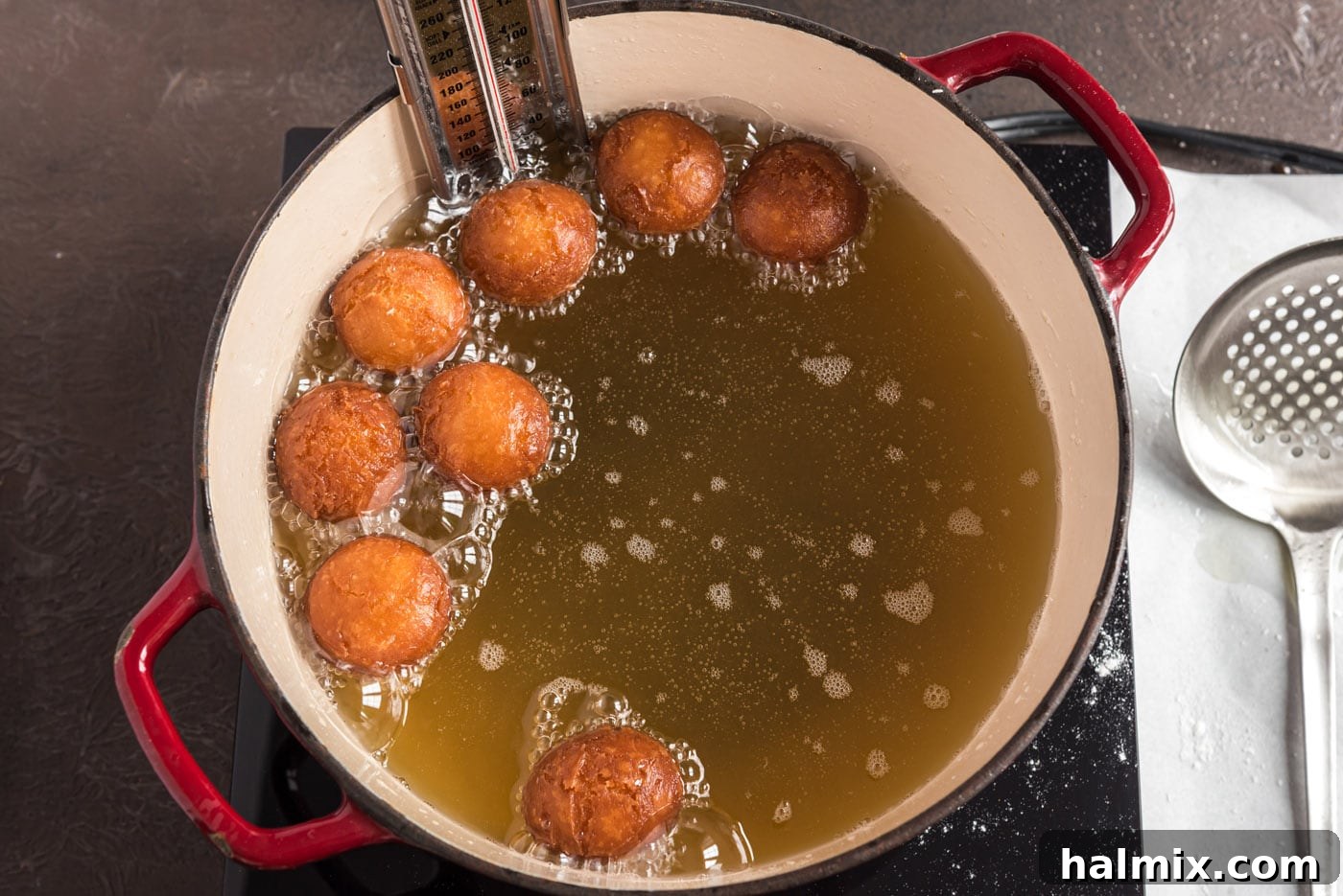 Fried donut holes lifted out of oil, golden and fluffy