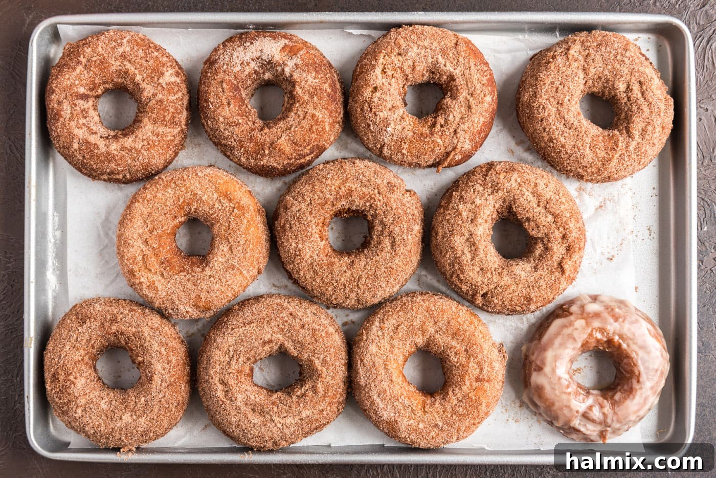 Cinnamon sugar coated donuts arranged on a baking sheet, ready to be devoured