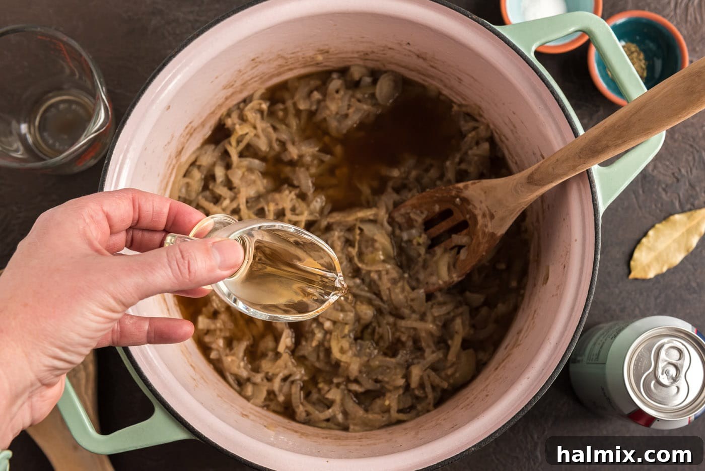 White wine vinegar being poured into the pot, providing a crucial acidic balance to the rich stew flavors.