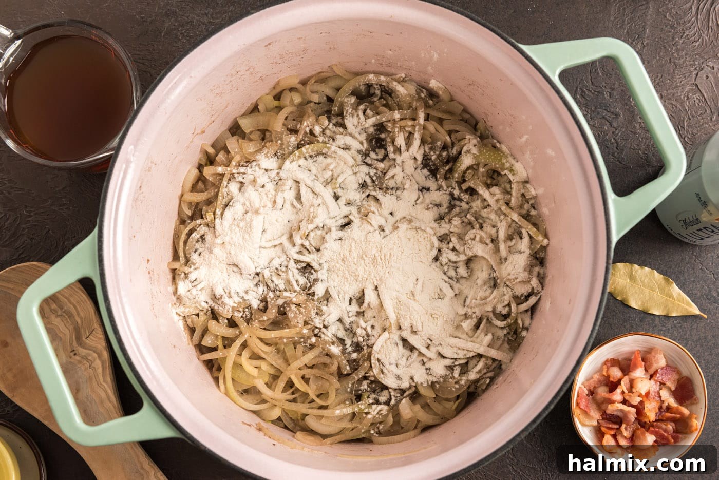 Flour being stirred into the softened onions in a Dutch oven, creating a savory roux for thickening the stew.
