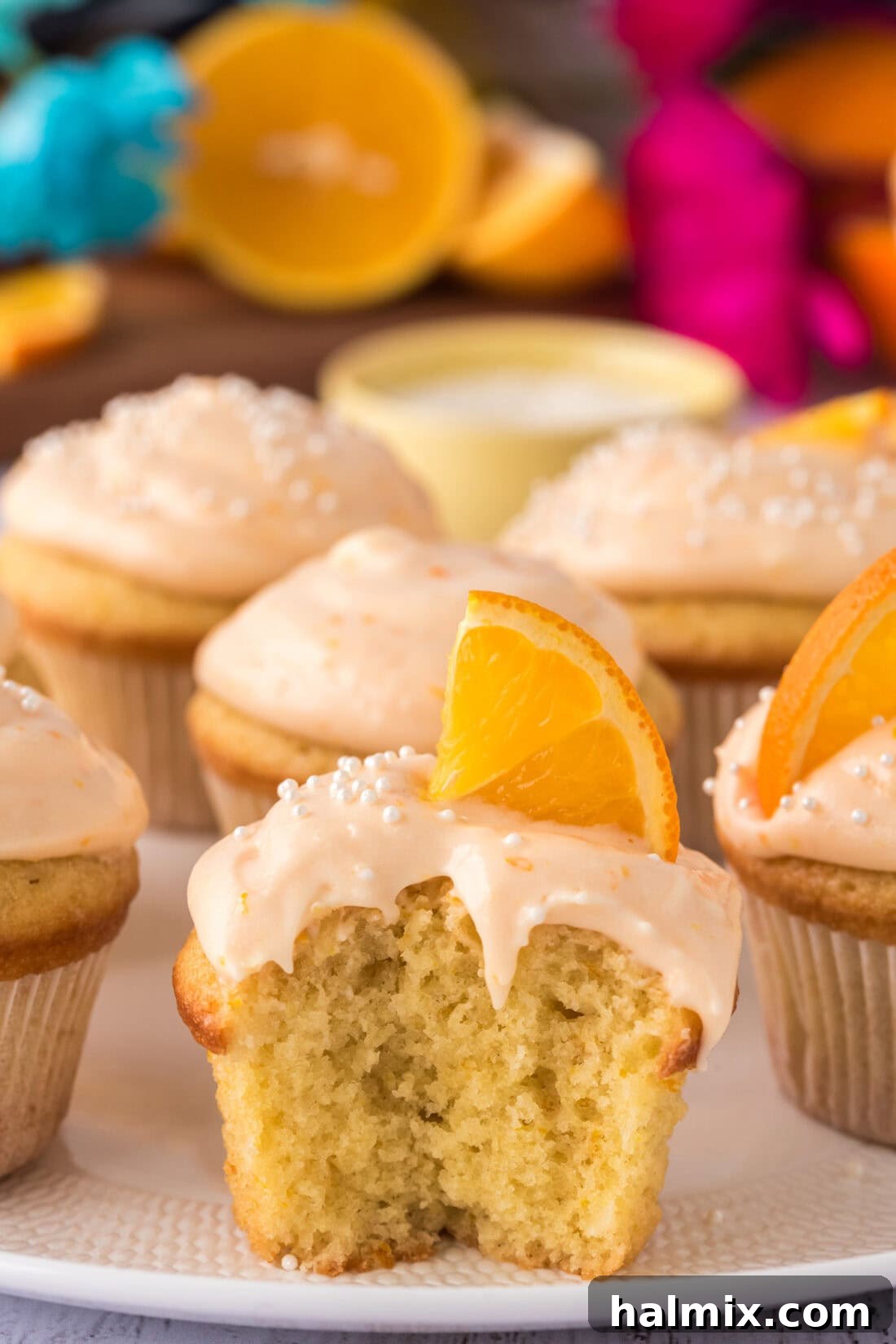 Orange Creamsicle Cupcake with a bite taken out, showing the fluffy interior and creamy frosting.