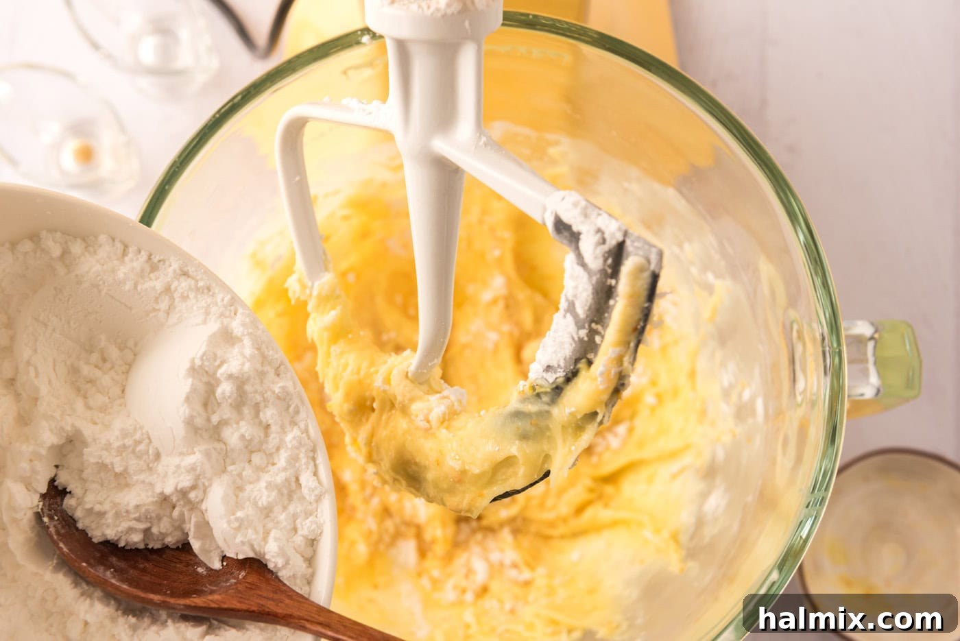 Adding confectioners' sugar to a bowl with cream cheese mixture for frosting.