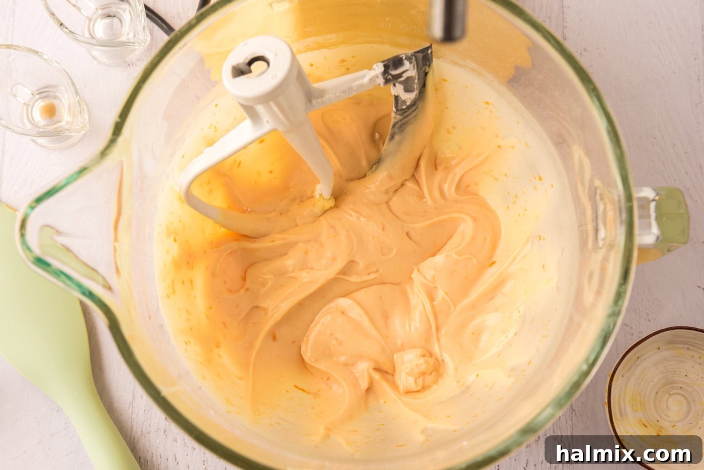 Orange creamsicle frosting in a stand mixer bowl, light and fluffy.