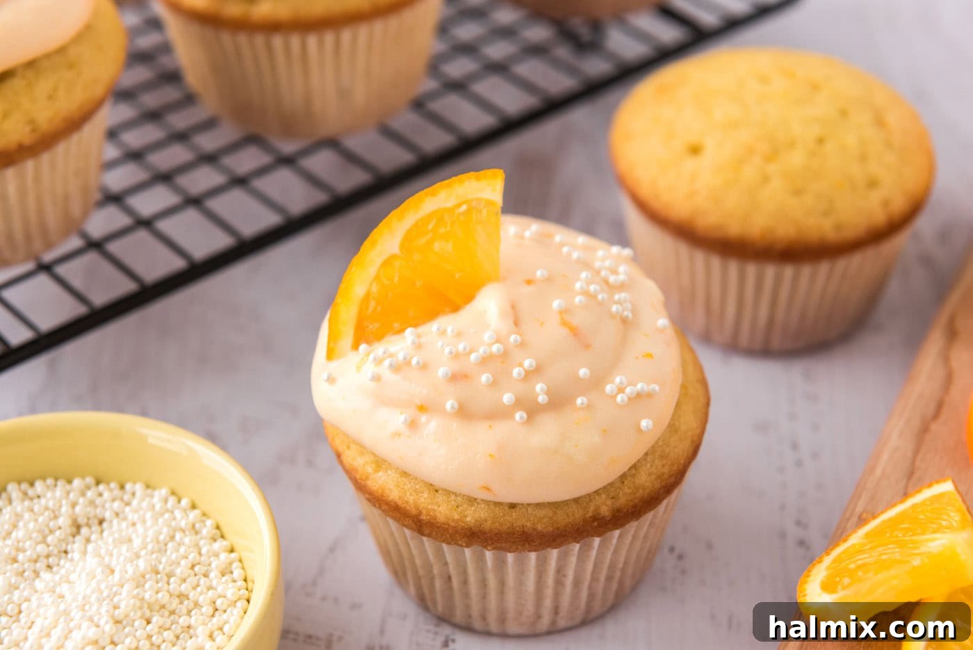 Finished creamsicle cupcakes garnished with orange wedges and sprinkles on a serving tray.