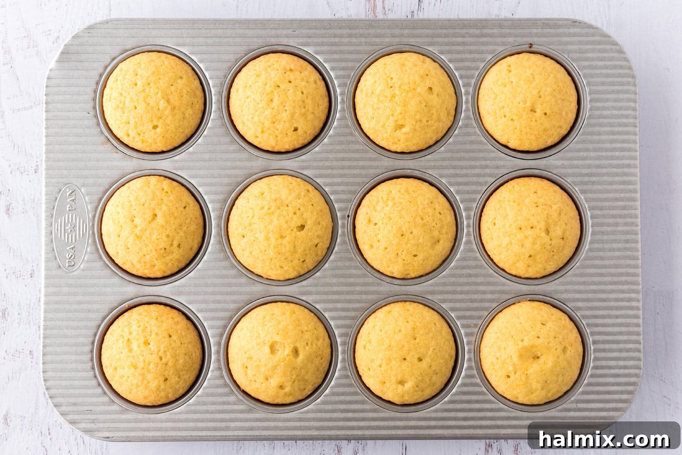 Baked orange creamsicle cupcakes in a pan, golden brown and perfectly risen.