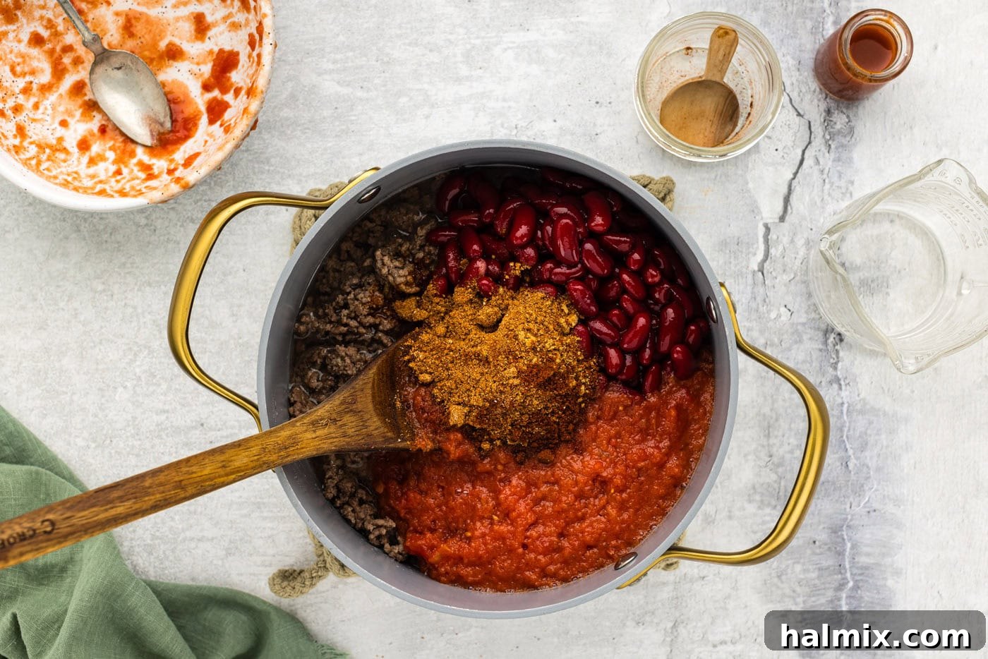 Southwest Chili Cornbread Stuffed Peppers 6 Ingredients like chili seasoning, tomatoes, and beans being added to a pot with browned ground beef