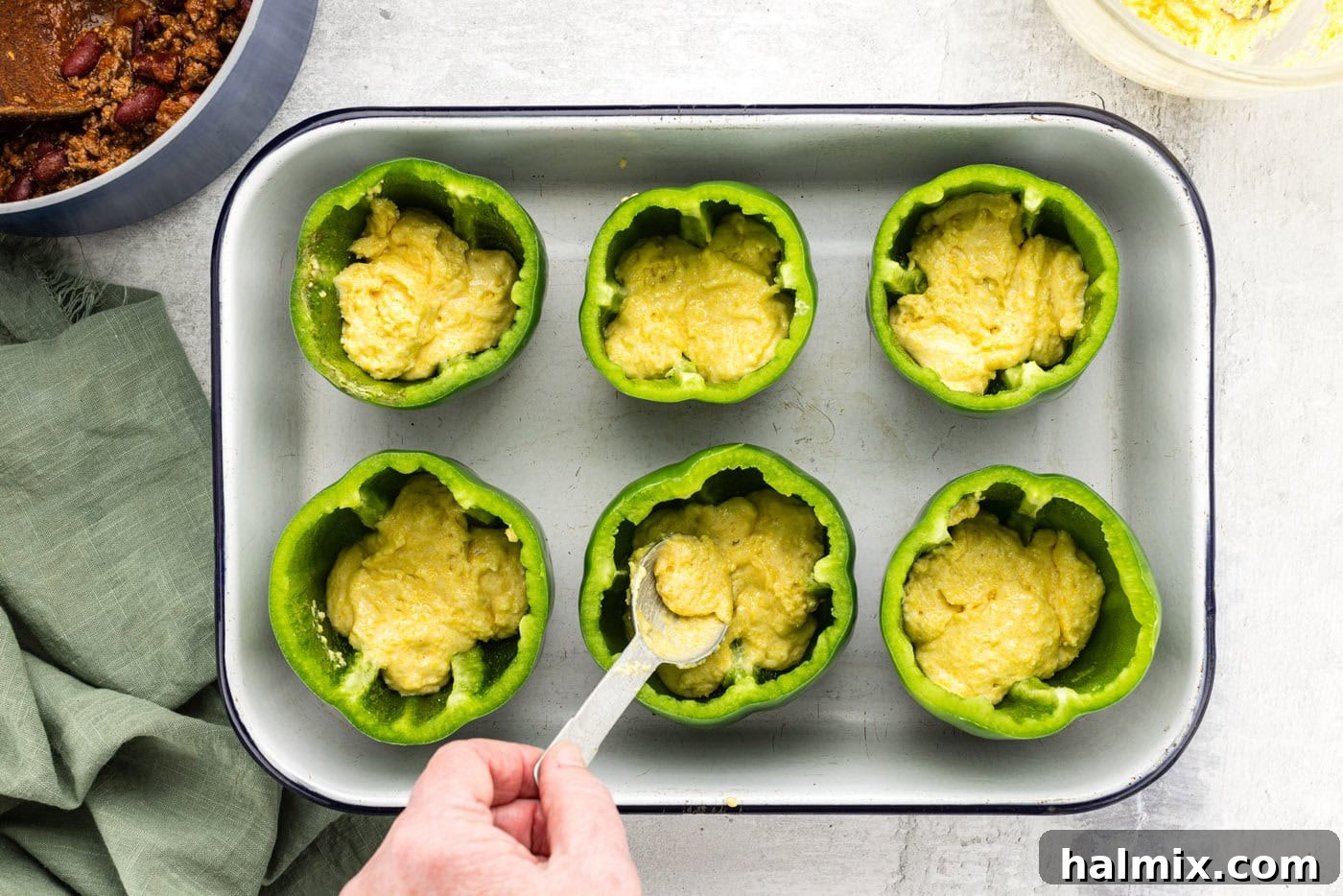 Southwest Chili Cornbread Stuffed Peppers 9 Spoonfuls of cornbread batter being added to the bottom of hollowed out bell peppers