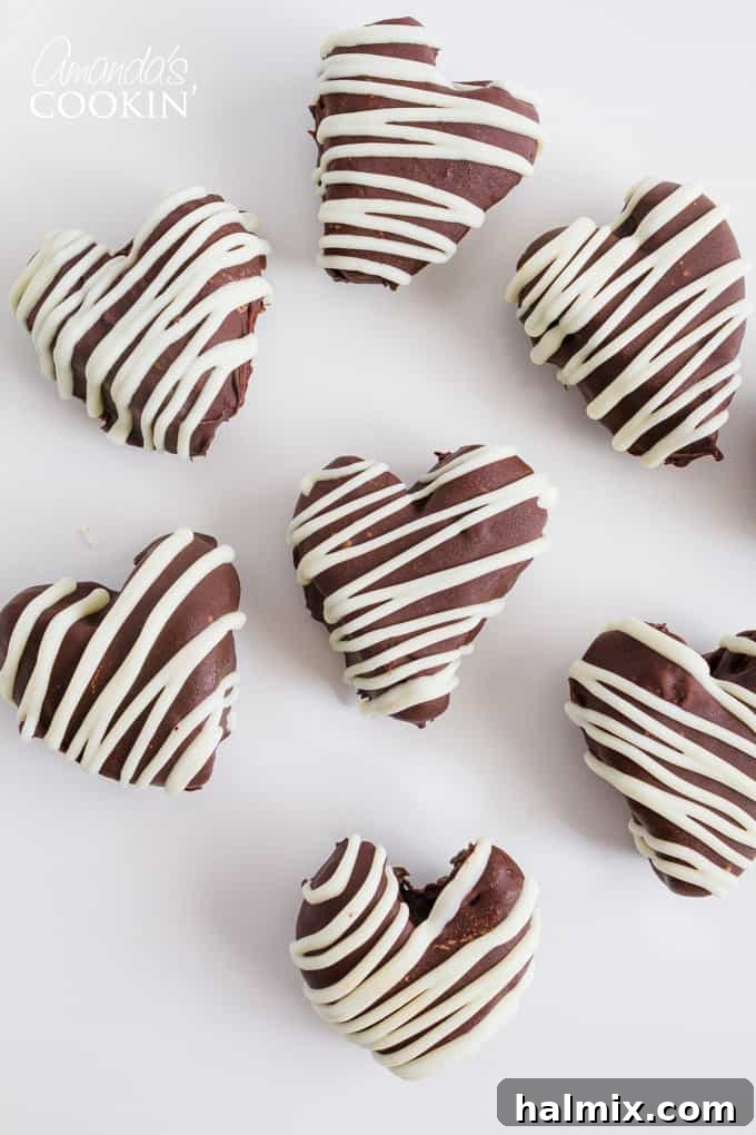 Seven heart-shaped Oreo truffles arranged artfully, each adorned with a delicate white chocolate drizzle.