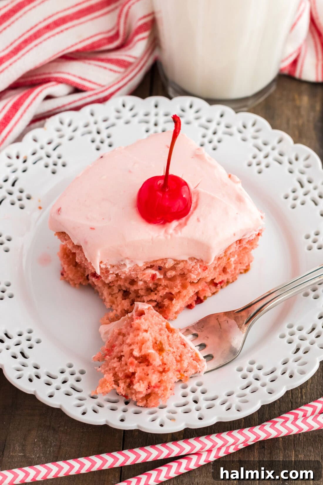 slice of cherry cake on a plate with a bite removed onto a fork