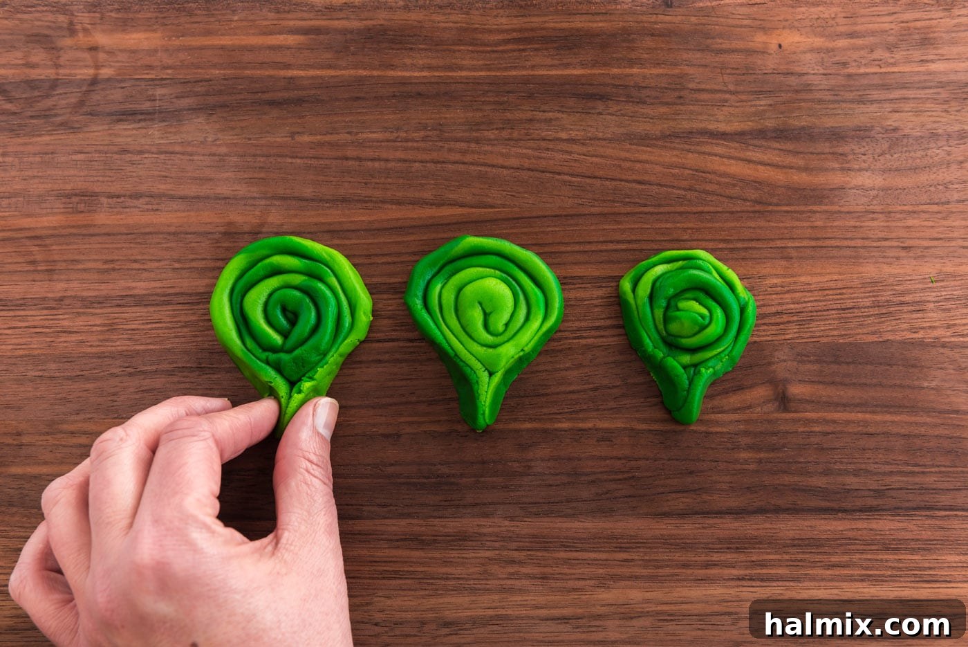 pinching ends of coiled green cookie dough
