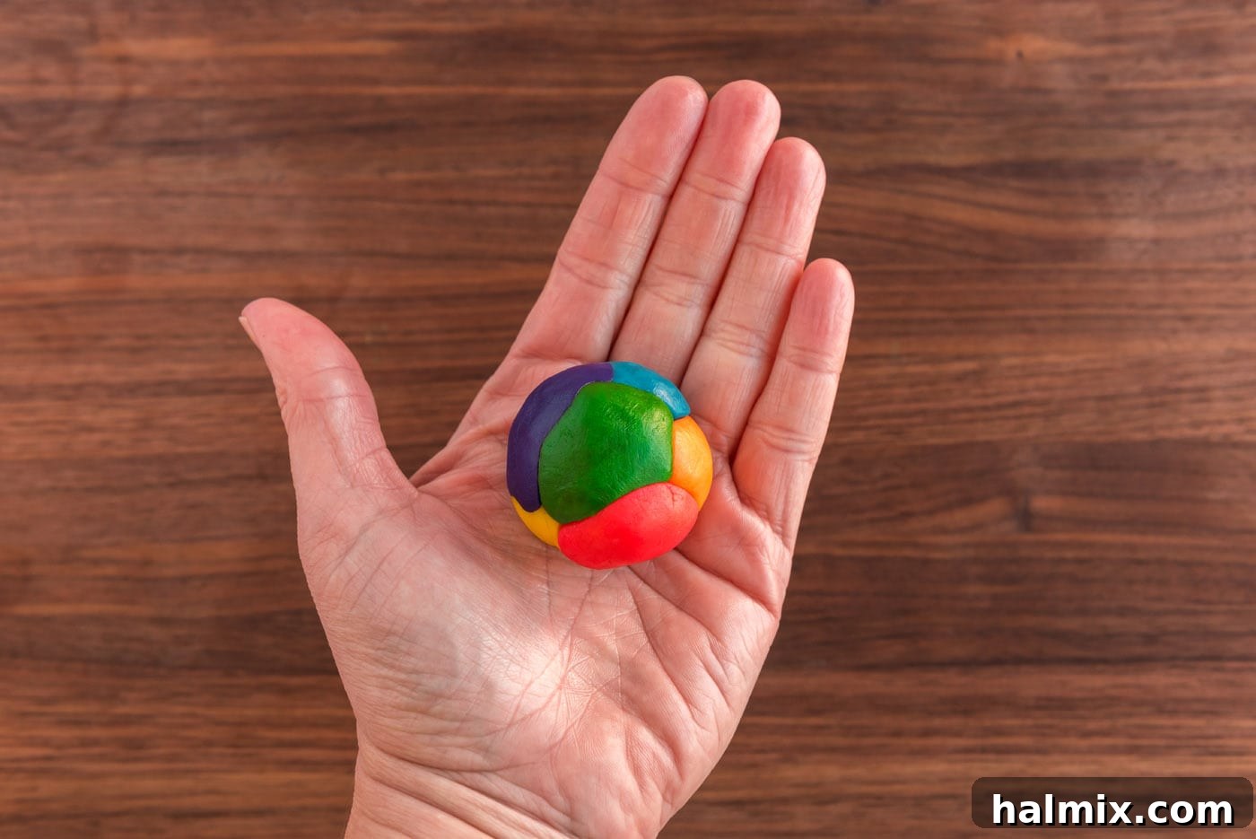 hand holding a ball of colorful cookie dough