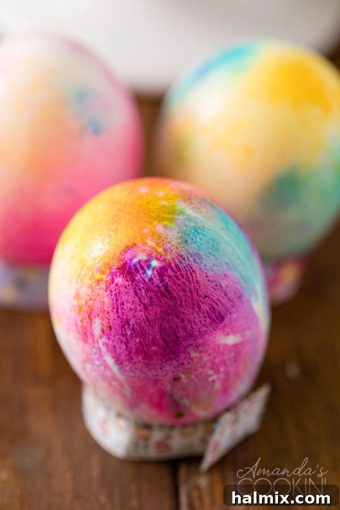 Tie Dye Easter Eggs are super fun for kids to get creative and create tons of different beautifully colored Easter eggs! Try these tie dye method this year! A finished tie-dyed Easter egg showcasing vibrant patterns