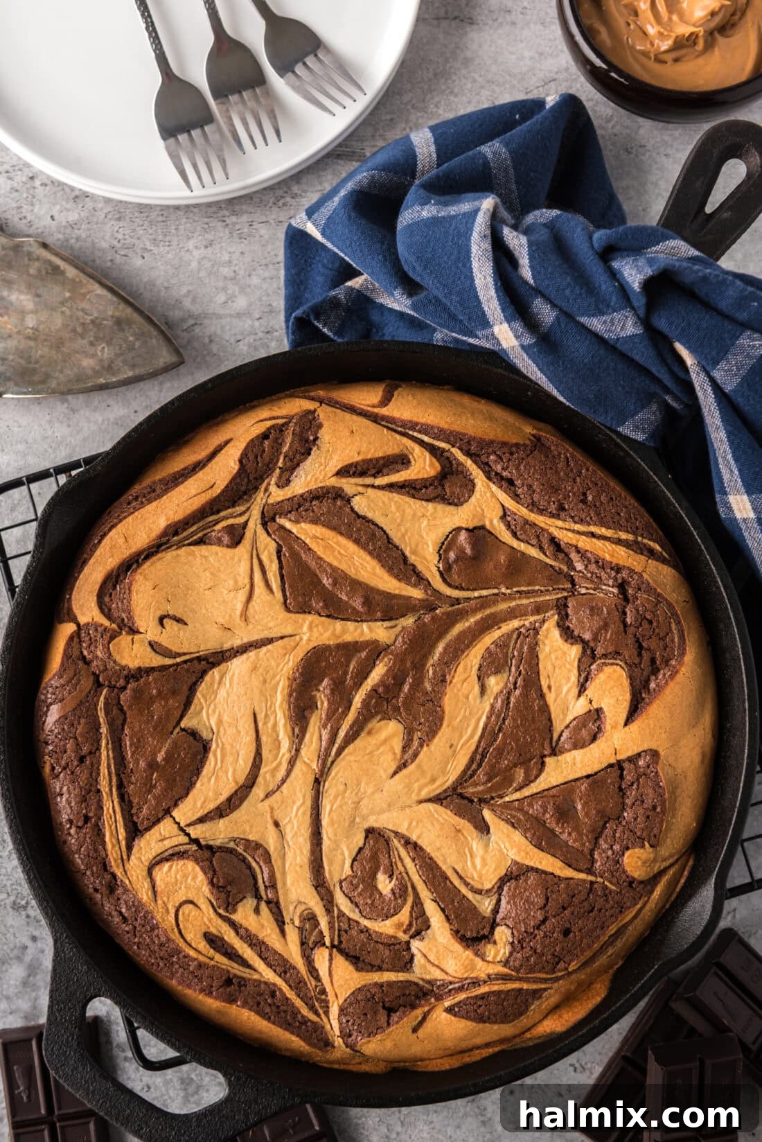 Peanut Butter Marbled Brownie Skillet Pie with plates in the background, a complete dessert ready to be served