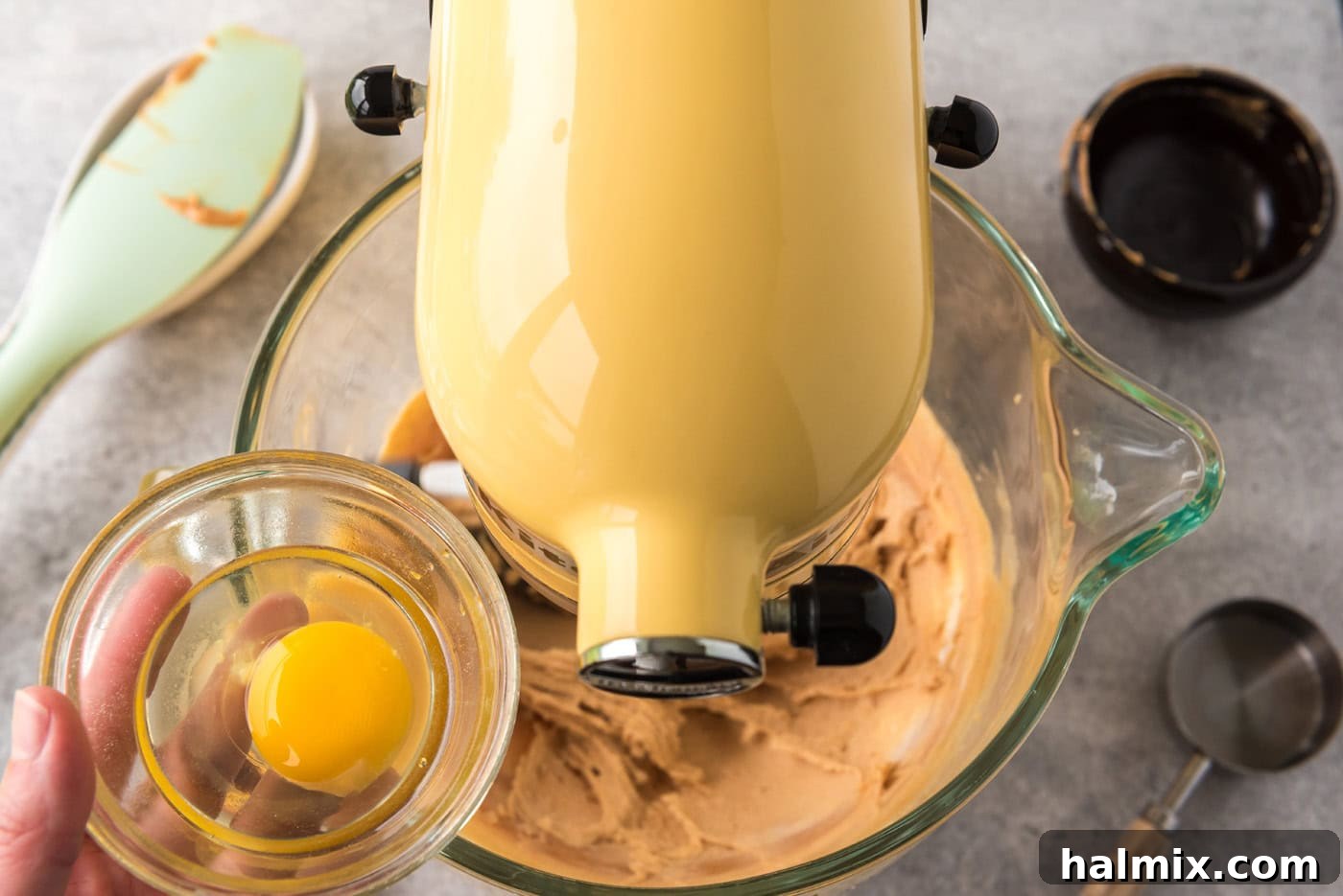 Adding eggs to a mixer bowl with peanut butter and cream cheese mixture, step 2