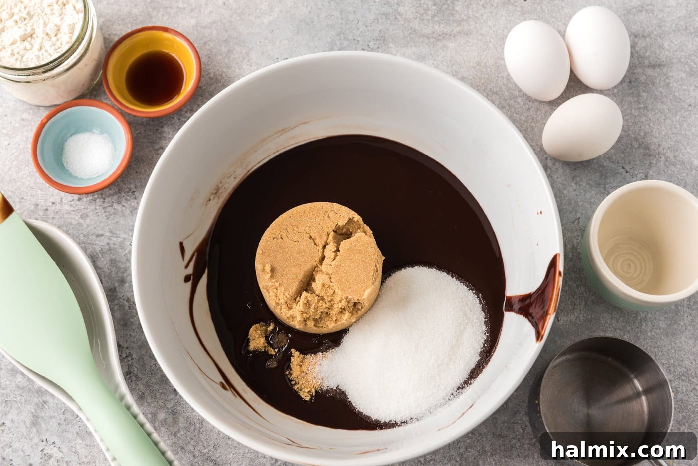 Brown sugar and granulated sugar added to melted chocolate mixture in a bowl, being stirred, step 3