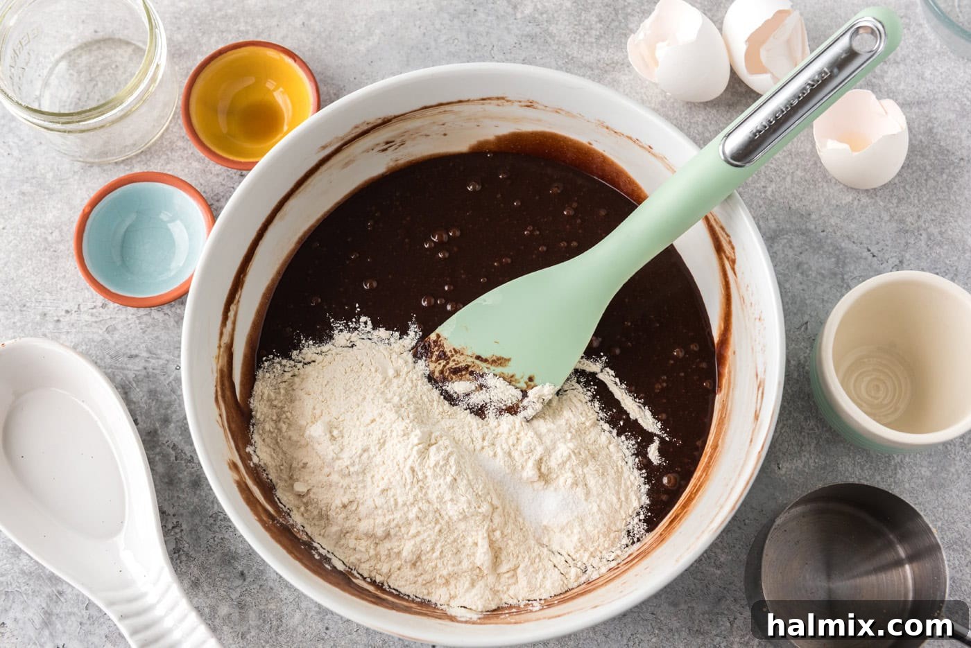 Dry ingredients (flour and salt) being added to a bowl of brownie batter and gently mixed with a rubber spatula, step 4