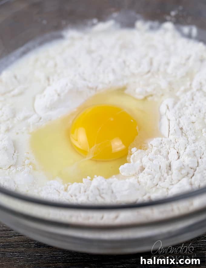 A visual step demonstrating an egg being carefully whisked into the flour and milk mixture, creating a consistent batter.