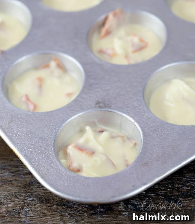 A mini muffin tray showcasing perfectly portioned pizza puff batter, neatly filled and ready for baking.