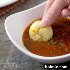 A pizza puff being dunked in a white bowl of pizza sauce.