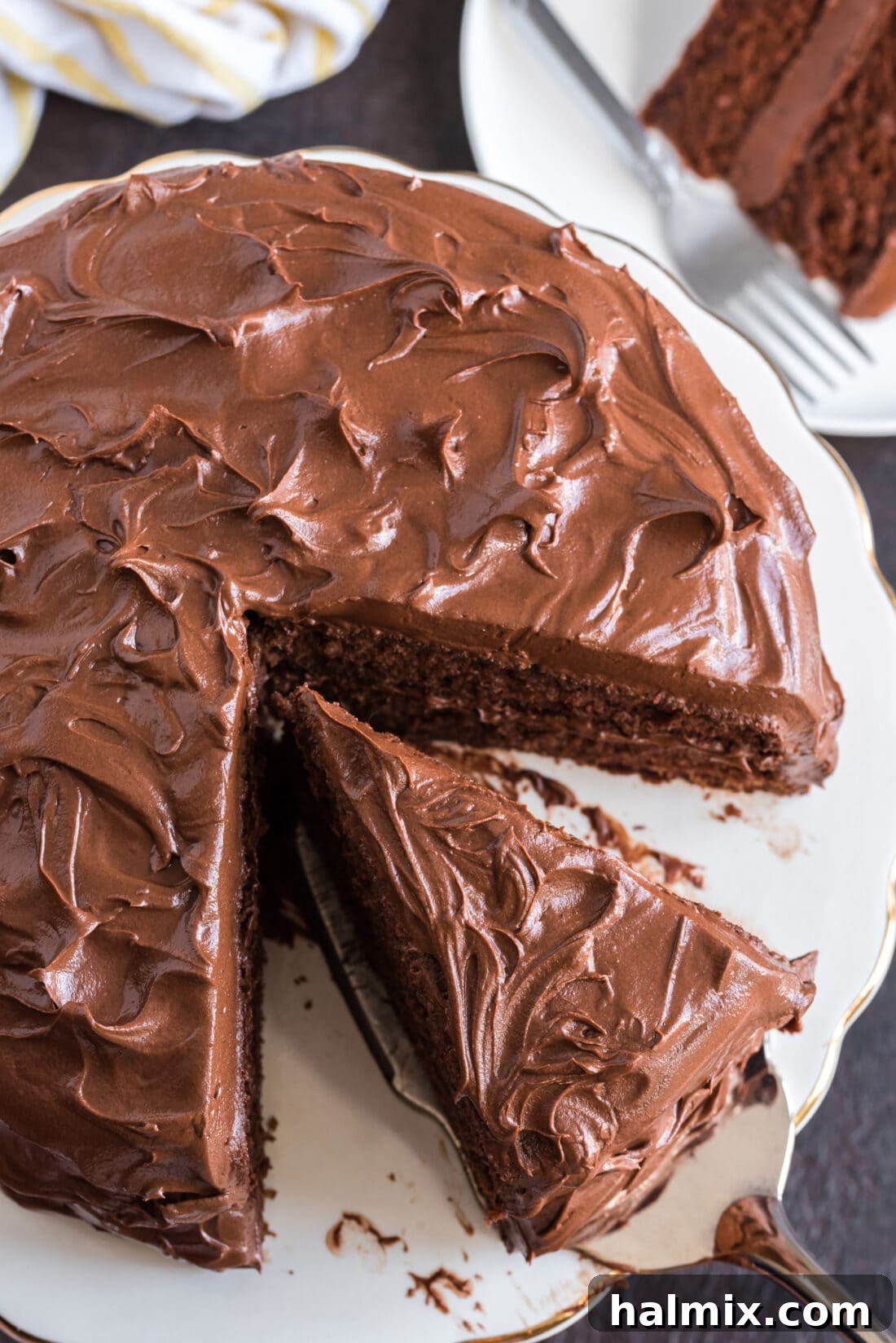 Overhead photo of a piece of Nigella's Chocolate Fudge Cake being removed from the cake