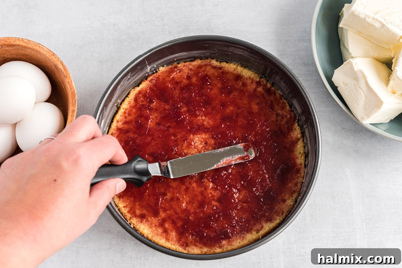 Regal Trifle Cheesecake 7 Spreading raspberry preserves over the yellow cake layer in the springform pan