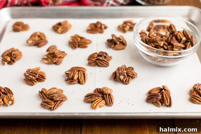 Small, neat mounds of toasted pecans arranged on a baking sheet lined with parchment paper, ready for caramel.