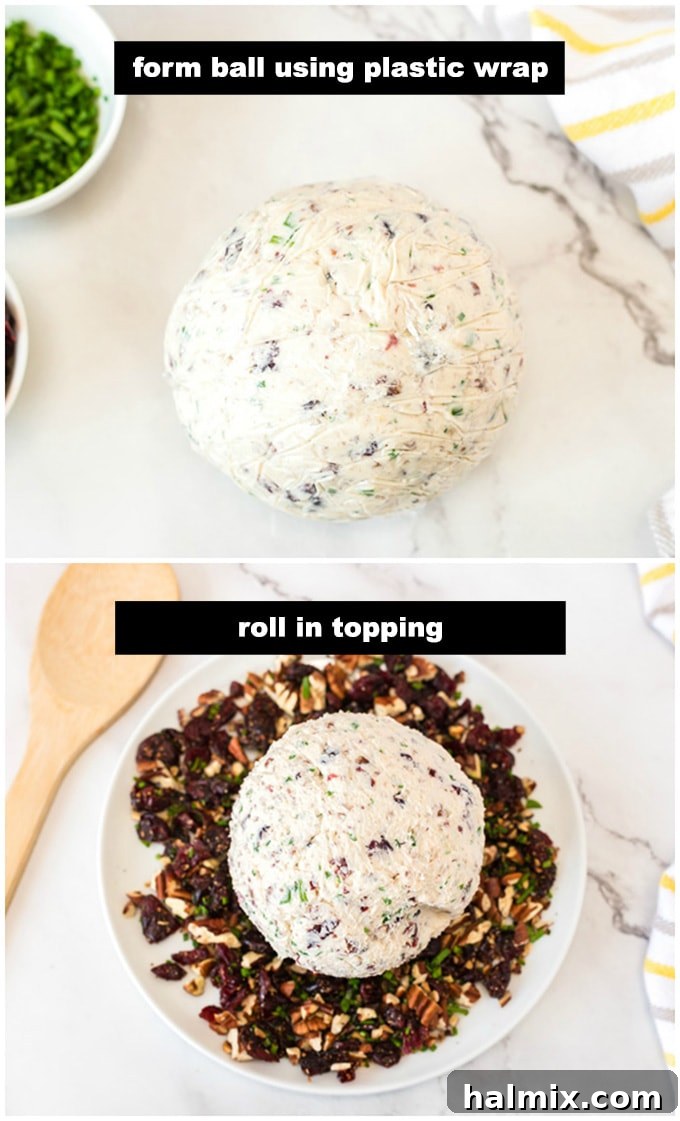 Shaping the cranberry cheese ball by hand, using plastic wrap to create a perfectly rounded form before coating. Hands carefully rolling the cheese mixture into a ball using plastic wrap.