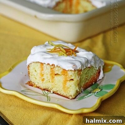 A piece of citrus lover's poke cake on a square plate, garnished with fresh fruit or zest.