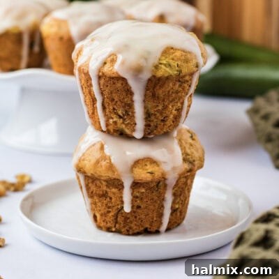 Stack of two Shortcut Zucchini Muffins, highlighting their fluffy texture and speckles of zucchini.