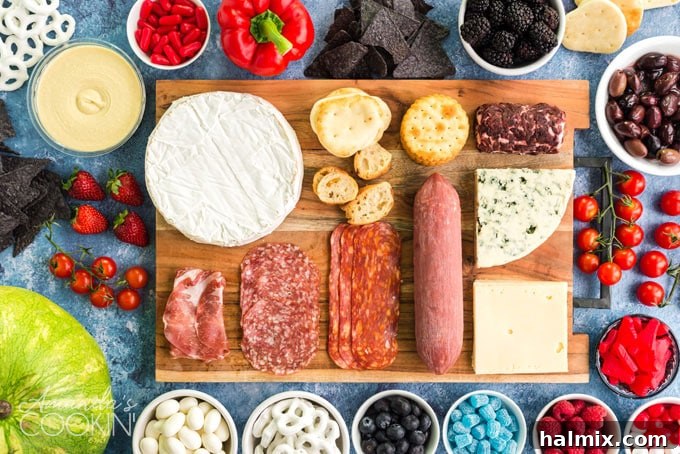 Various ingredients for a patriotic charcuterie board, including meats, cheeses, fruits, and crackers, neatly laid out on a wooden cutting board before assembly.