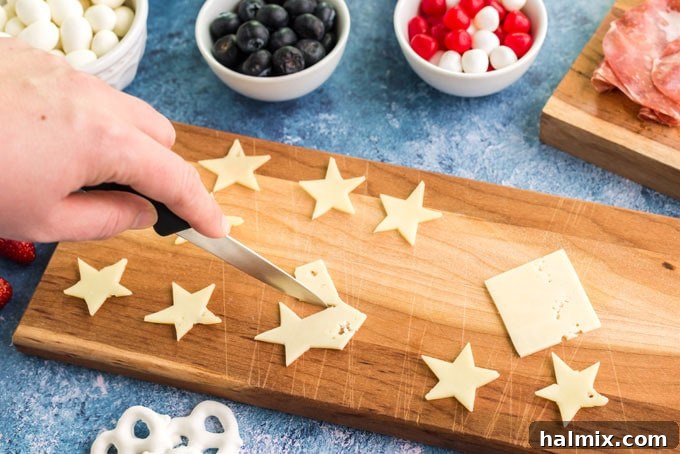 Hands using a star-shaped cookie cutter to transform cheese slices into festive star shapes, a simple yet effective way to add a patriotic touch to a charcuterie board.