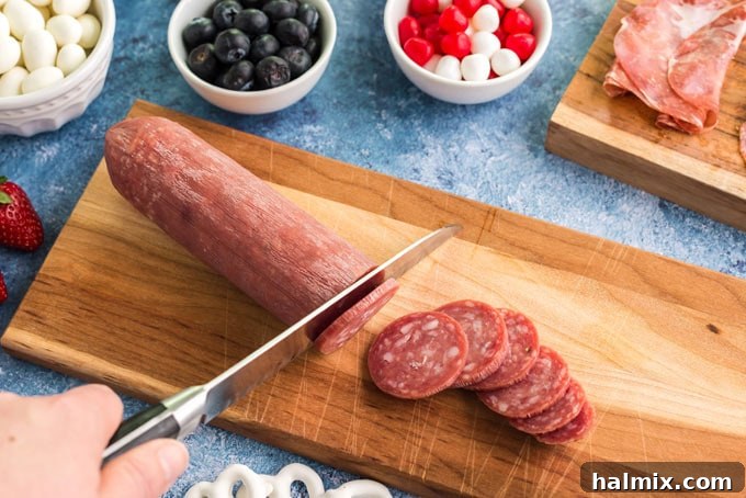 A hand skillfully slicing salami into thin, uniform pieces on a wooden cutting board, preparing the meat for a charcuterie board.