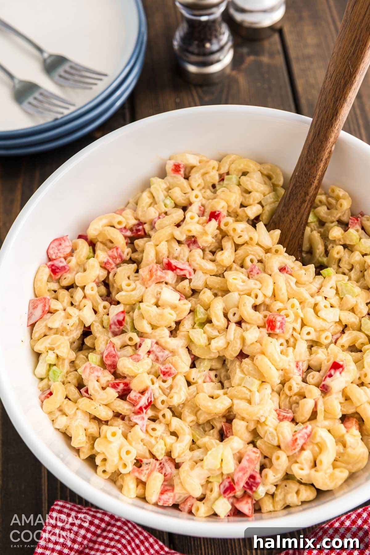 Classic Macaroni Salad for Barbecues, Potlucks, and Holidays An overhead shot of a white bowl filled with creamy macaroni salad, garnished with a sprinkle of paprika and fresh parsley.