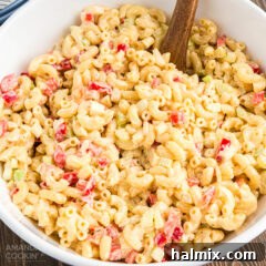 A bowl of macaroni salad with a wooden spoon, ready to be served.