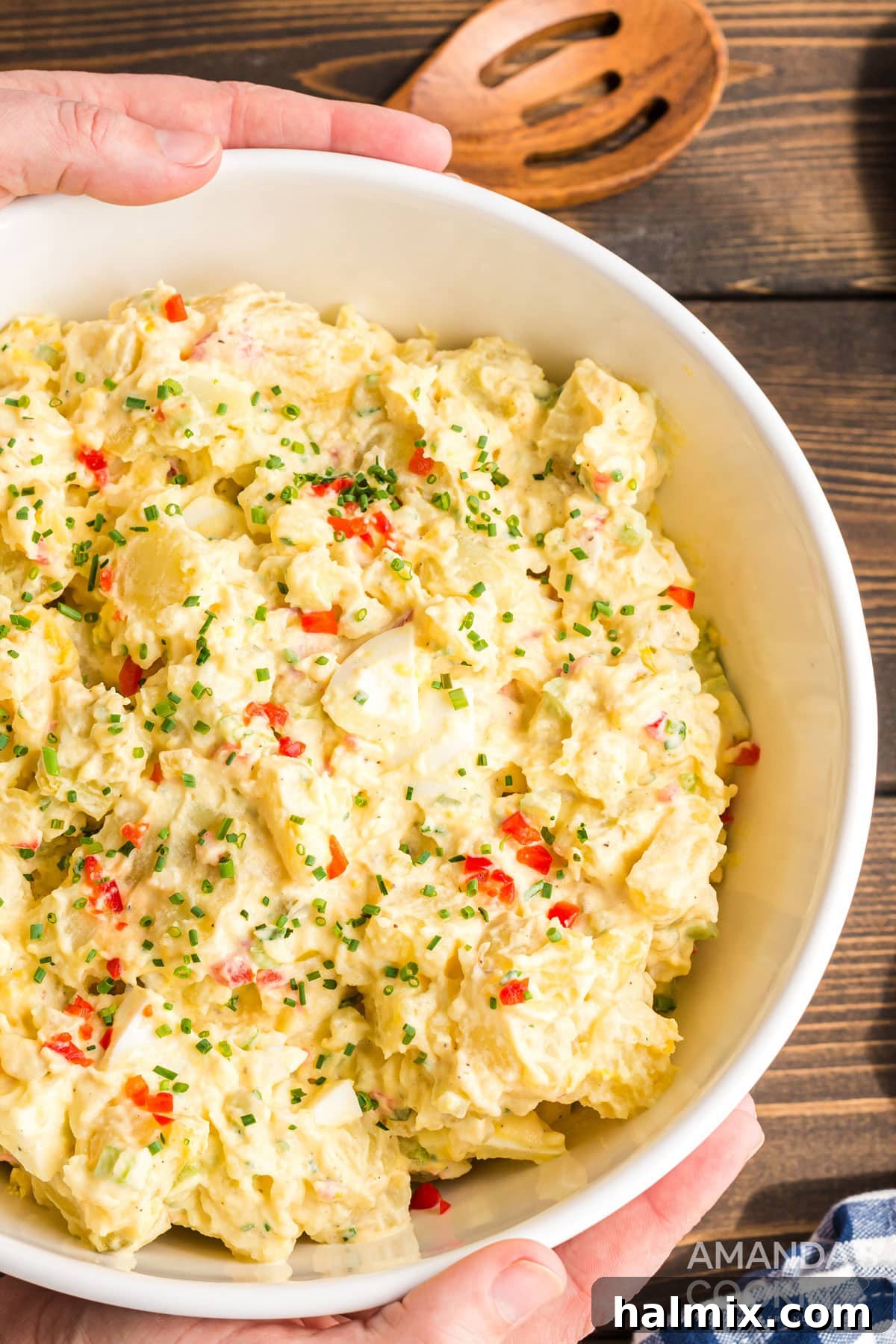 If you're looking for that perfect potato salad, you have to try my mom's recipe. I love my mom's potato salad, it's a classic and the hit of the party! hands around large bowl of potato salad
