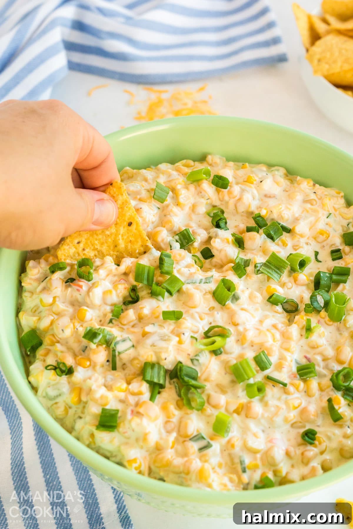 hand scooping corn dip with tortilla chip