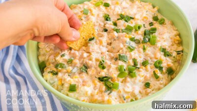 hand dipping tortilla chip in corn dip