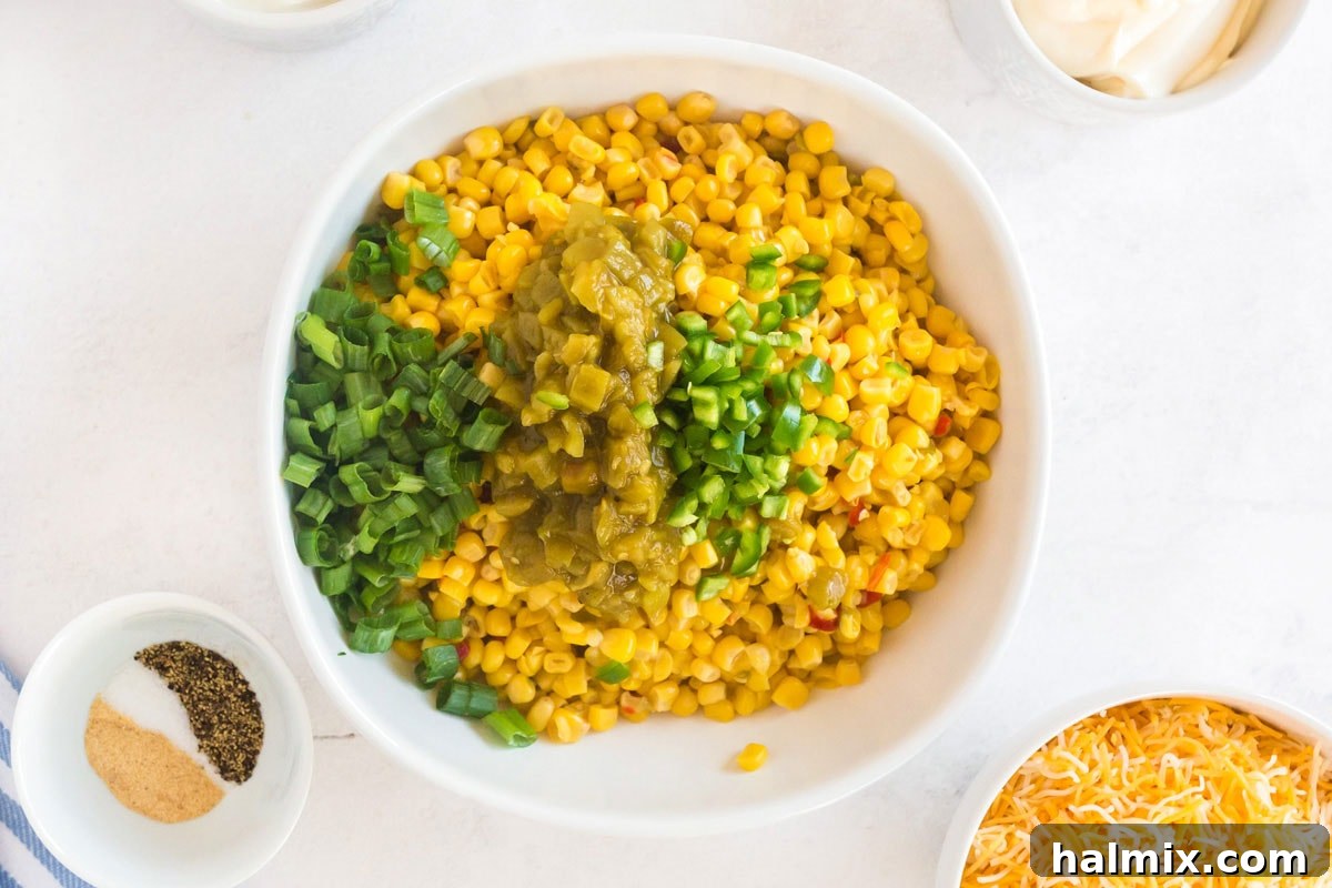 bowl of corn with green chiles, jalapeno, and green onion added, vibrant and ready for cream base