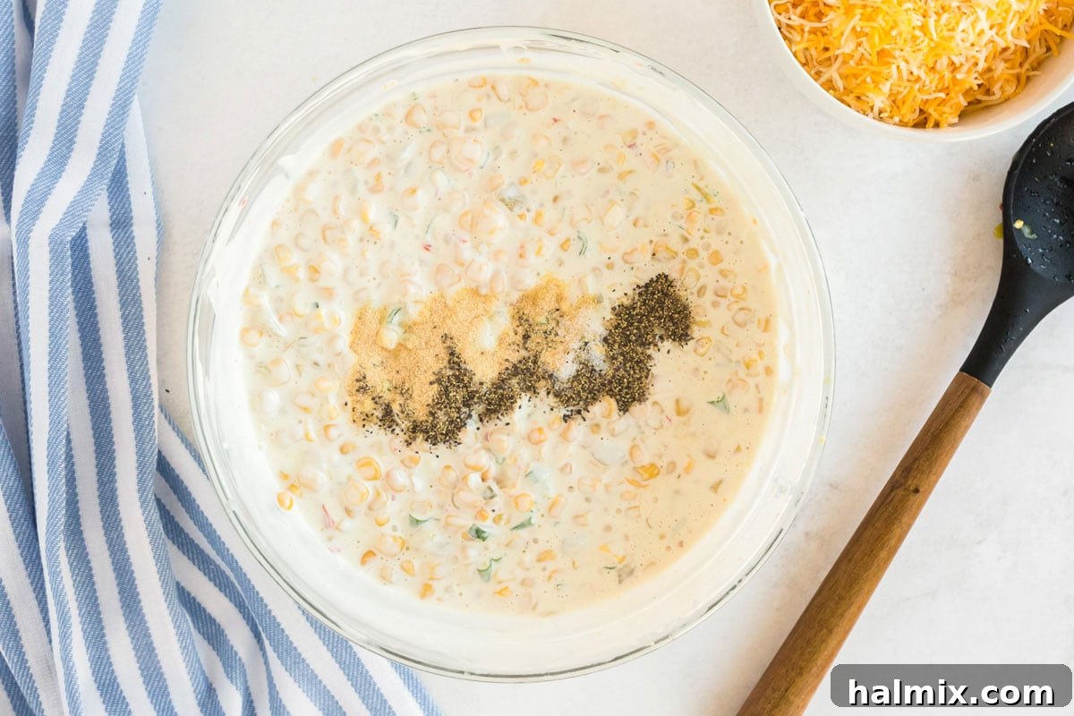 bowl of corn dip with seasonings added to the top of it, ready for final mix