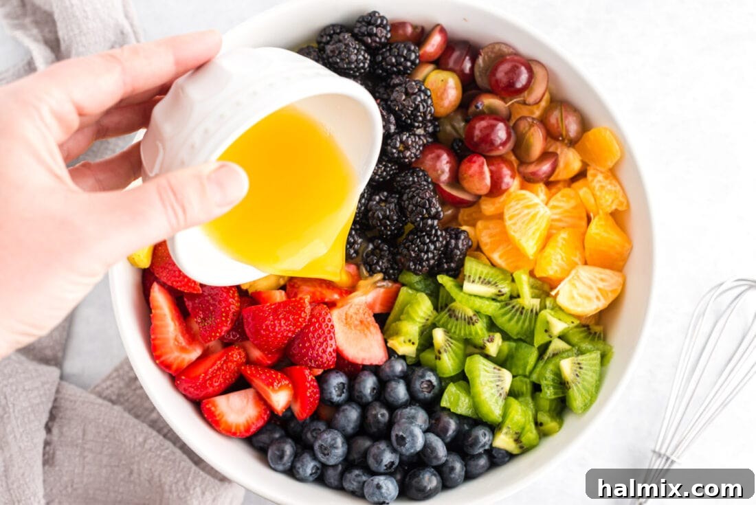 Rainbow Fruit Delight 4 Freshly cut fruit tossed with dressing in a large bowl, ready for chilling