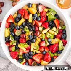A beautiful bowl of fresh fruit salad, glistening with dressing and vibrant colors