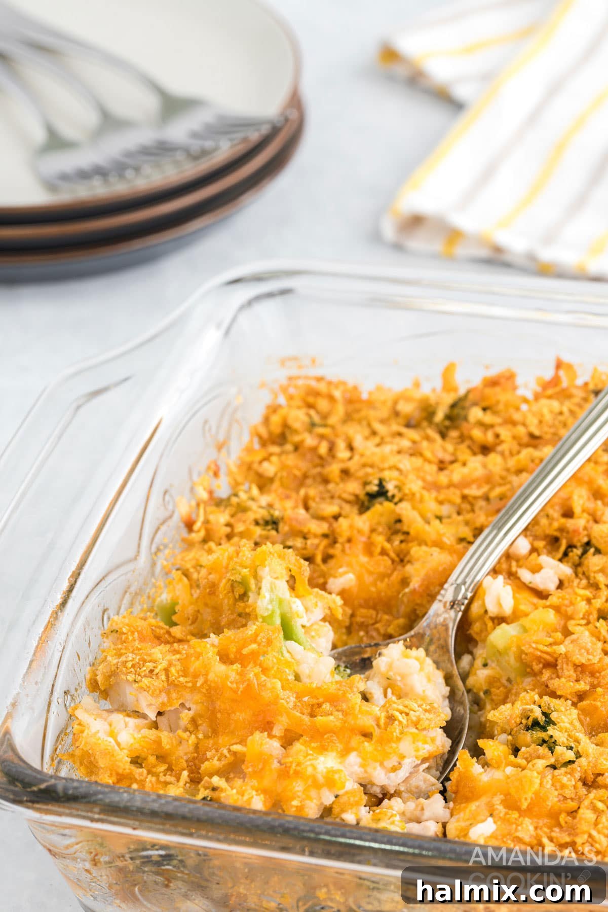 A glass baking dish showcasing a generous serving of creamy Chicken Broccoli Rice Casserole, with a spoon ready to scoop