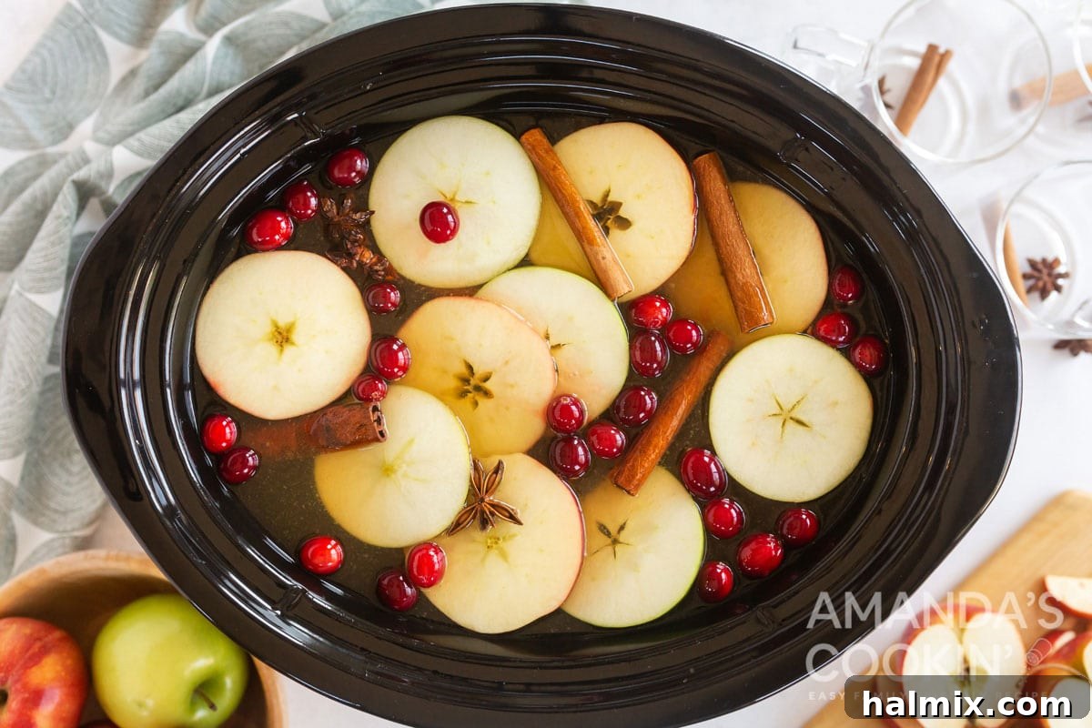 Hot apple cider simmering in a slow cooker (crockpot), ready to be served, showing its rich color.
