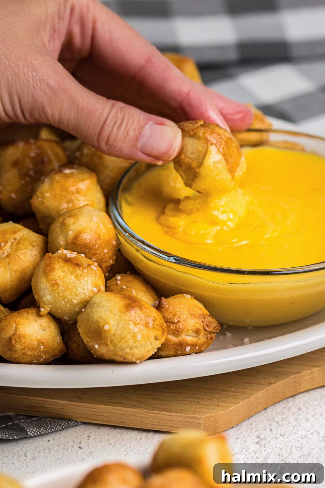 Golden Air Fried Pretzel Poppers 3 Air Fryer Pretzel Bite being dipped into cheese sauce