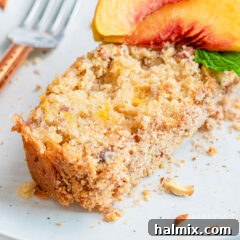 A close-up image of a perfectly baked slice of peach bread, showing its moist texture and visible peach pieces and almonds.
