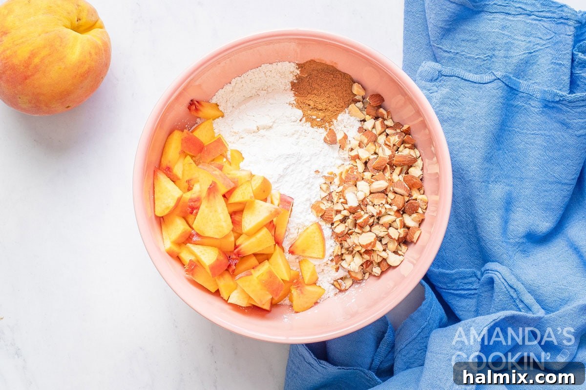 Golden Peach Loaf 4 A bowl containing dry ingredients, chopped peaches, and toasted almonds, ready to be combined for the peach bread batter.