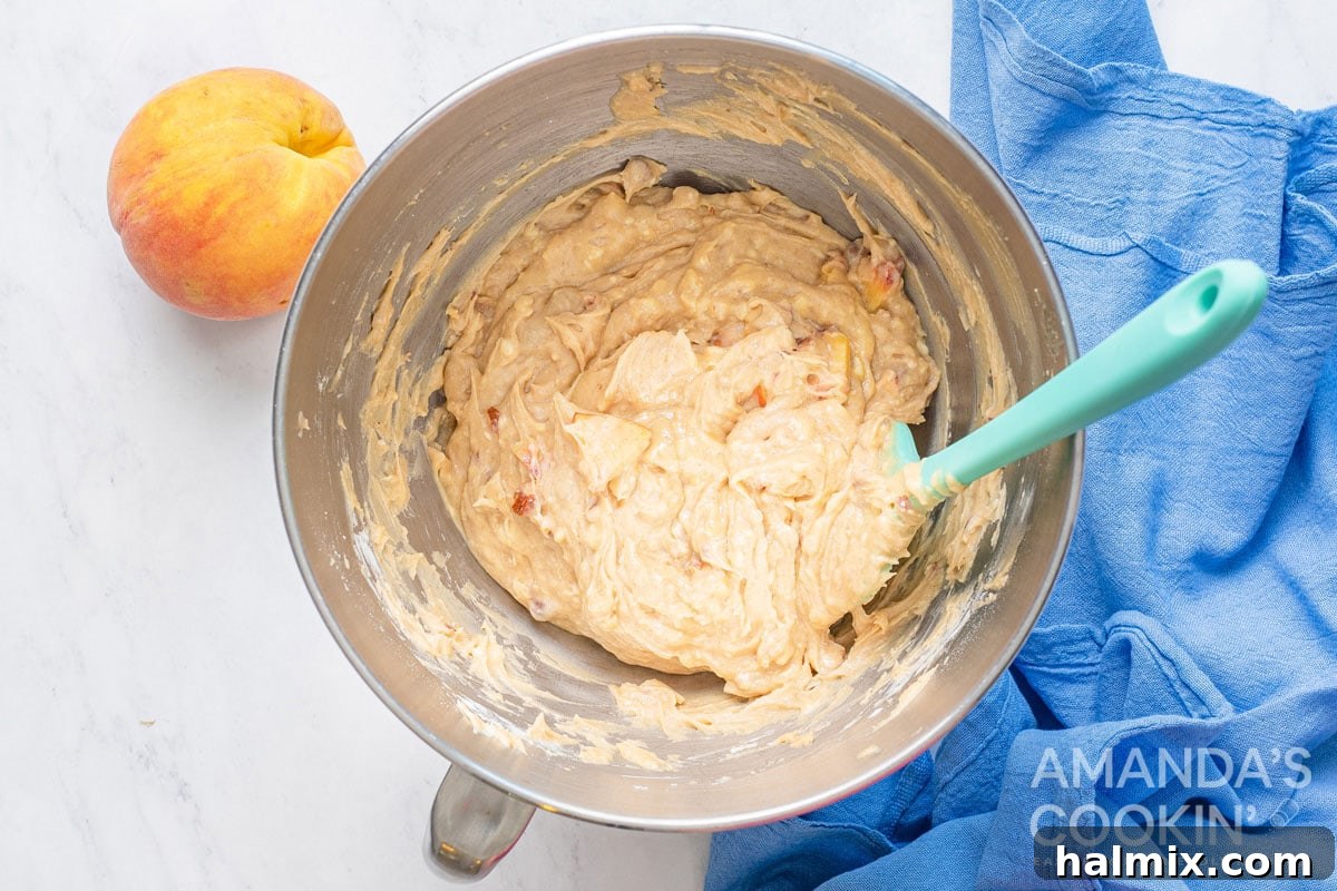 Golden Peach Loaf 5 A bowl filled with peach bread batter, featuring visible chunks of peach and almond, ready for the loaf pan.