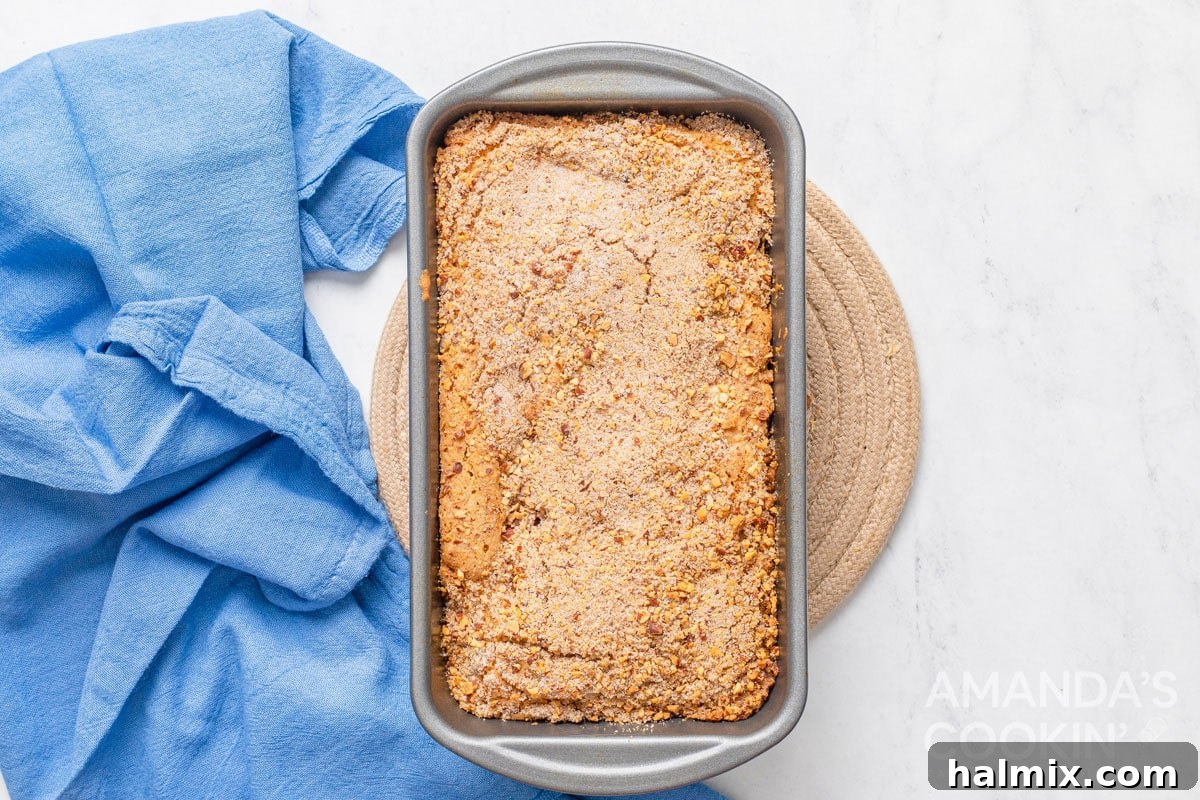 Golden Peach Loaf 7 A freshly baked, golden-brown peach bread loaf, still in its pan, removed from the oven and resting on a trivet.