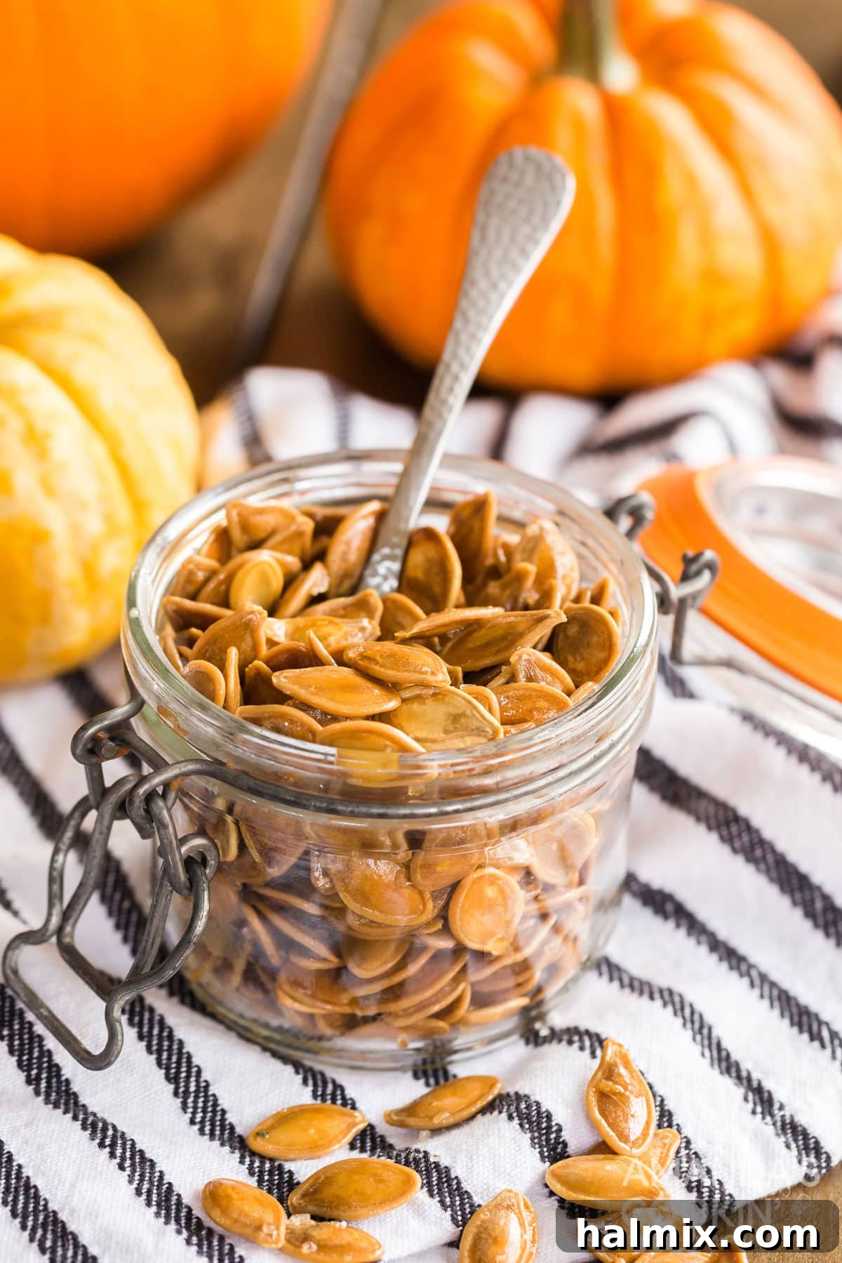 Small jar filled with perfectly roasted pumpkin seeds, ready for snacking, with a spoon nestled beside it.